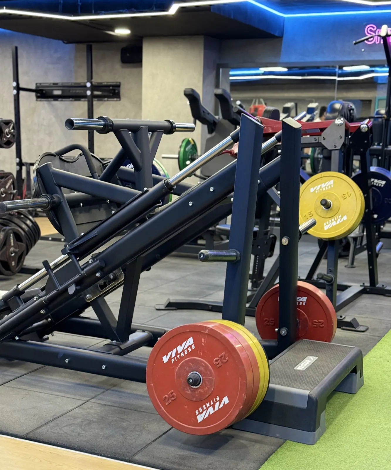 A plate-loaded hack squat with red and yellow bumper plates