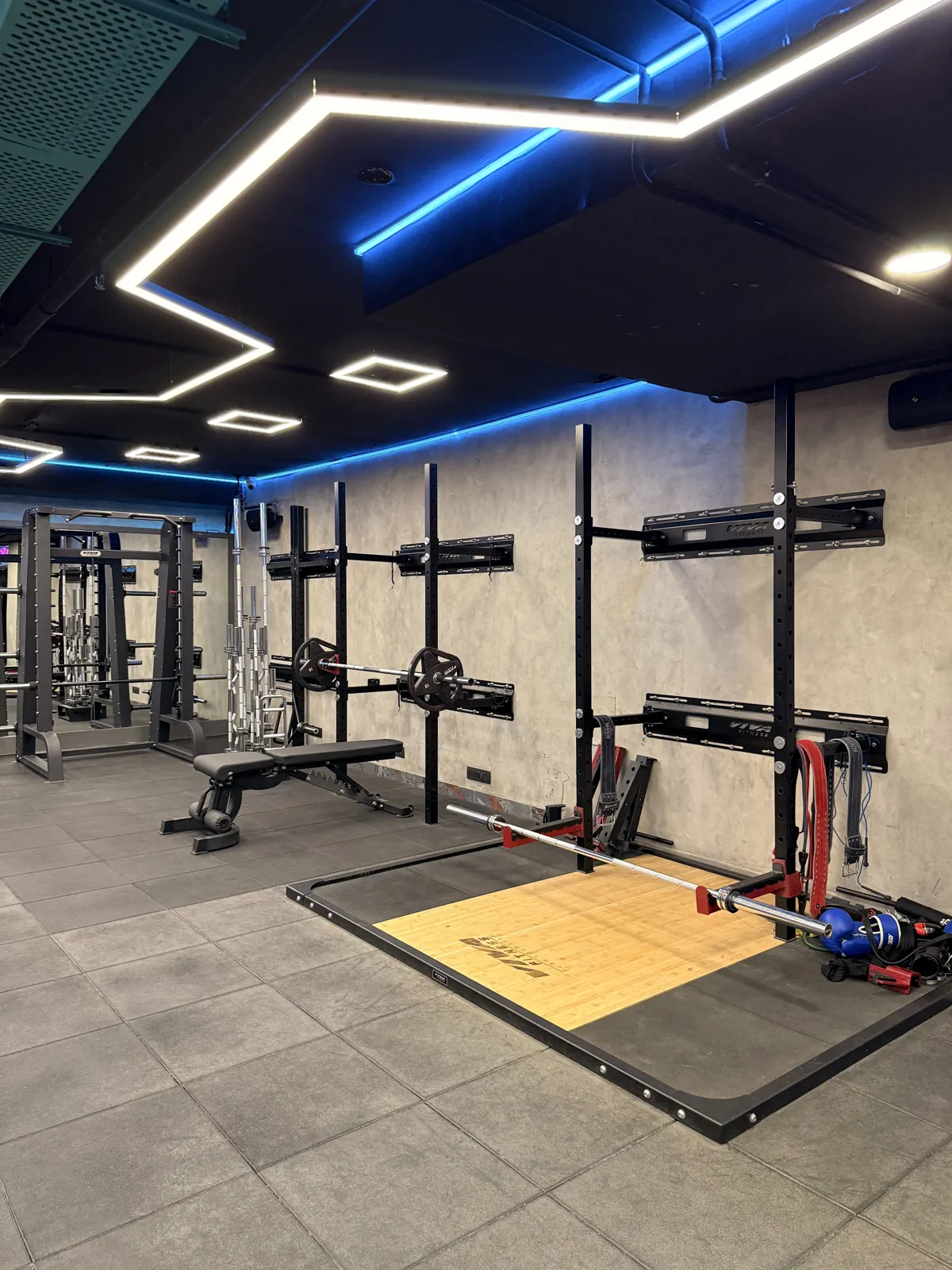 The lifting platform with a loaded barbell and wall-mounted rack
